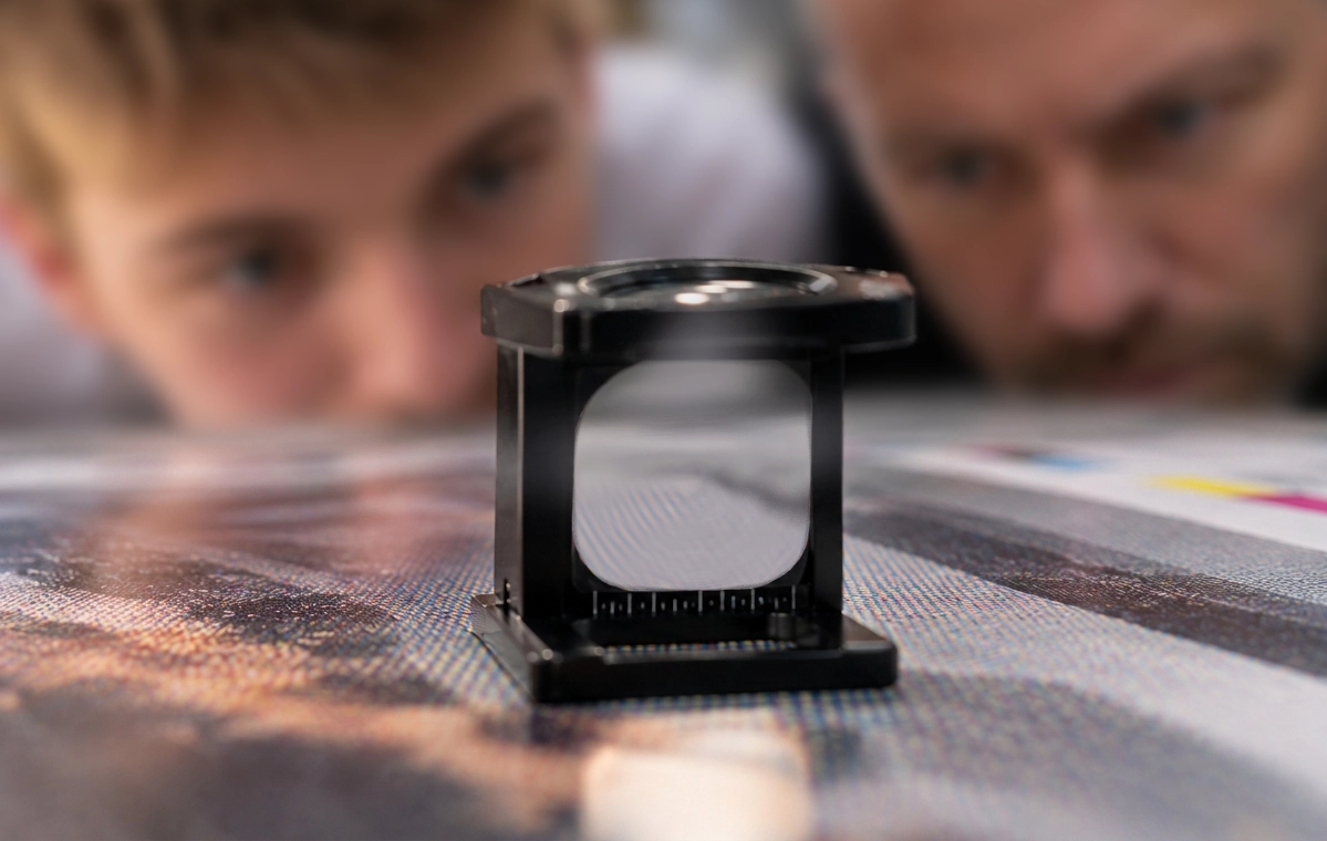 A child and his father examining a print through a linen tester